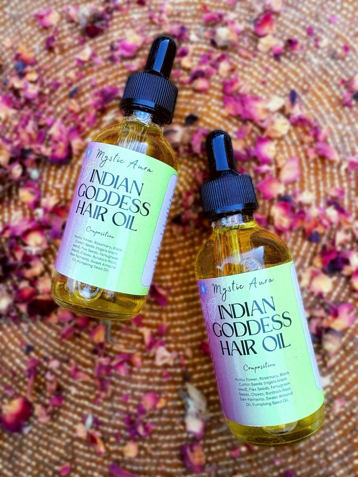 Two bottles of Indian Goddess Hair Oil on dried rose petals