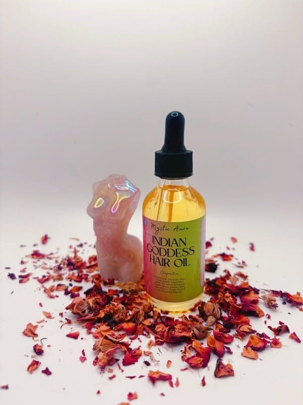 A bottle of Indian Goddess Hair Oil on rose petals